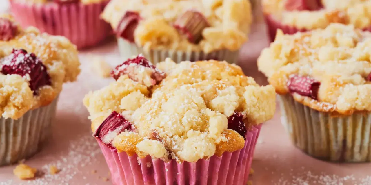 Saftige Rhabarber Muffins mit Streuseln, bestäubt mit Puderzucker. Ein Genuss für jeden Kaffeetisch.
