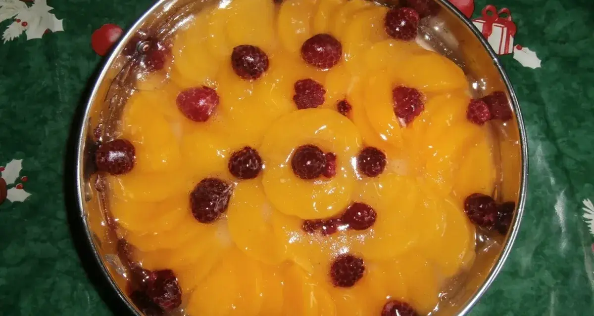 Fruchtiger Tortenboden ohne Ei, belegt mit Pfirsichspalten und Himbeeren in Gelee.