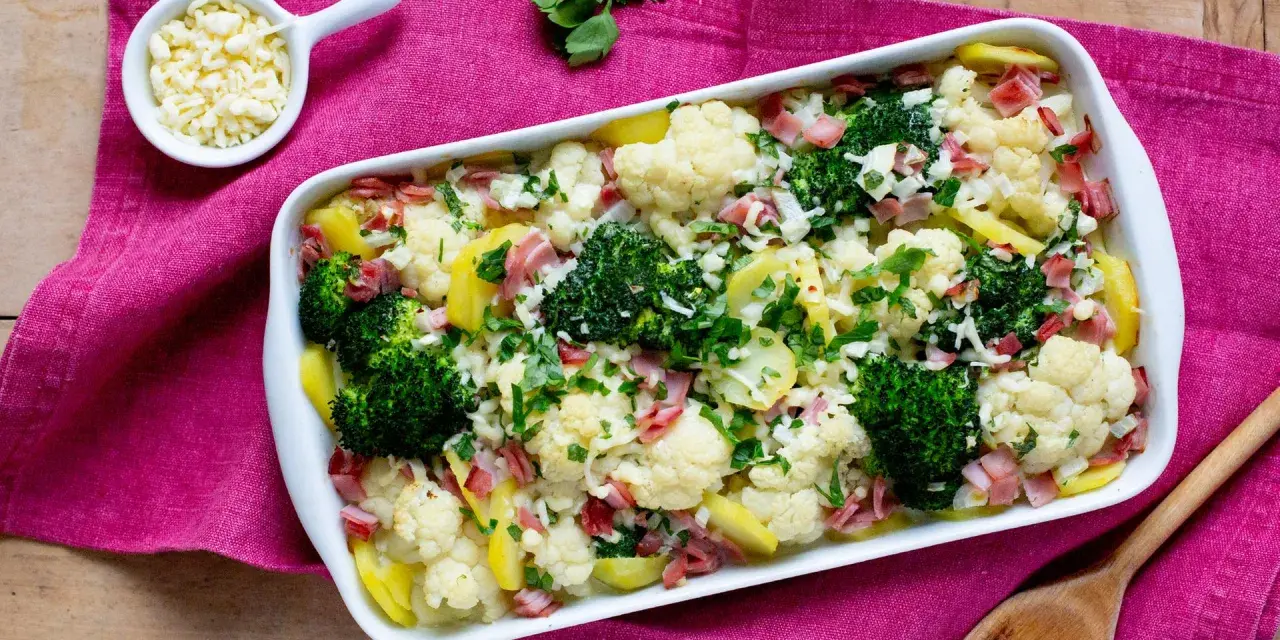 Ein herzhafter Blumenkohl-Brokkoli-Auflauf mit Kartoffeln und Schinken, bestreut mit frischer Petersilie und Käse.