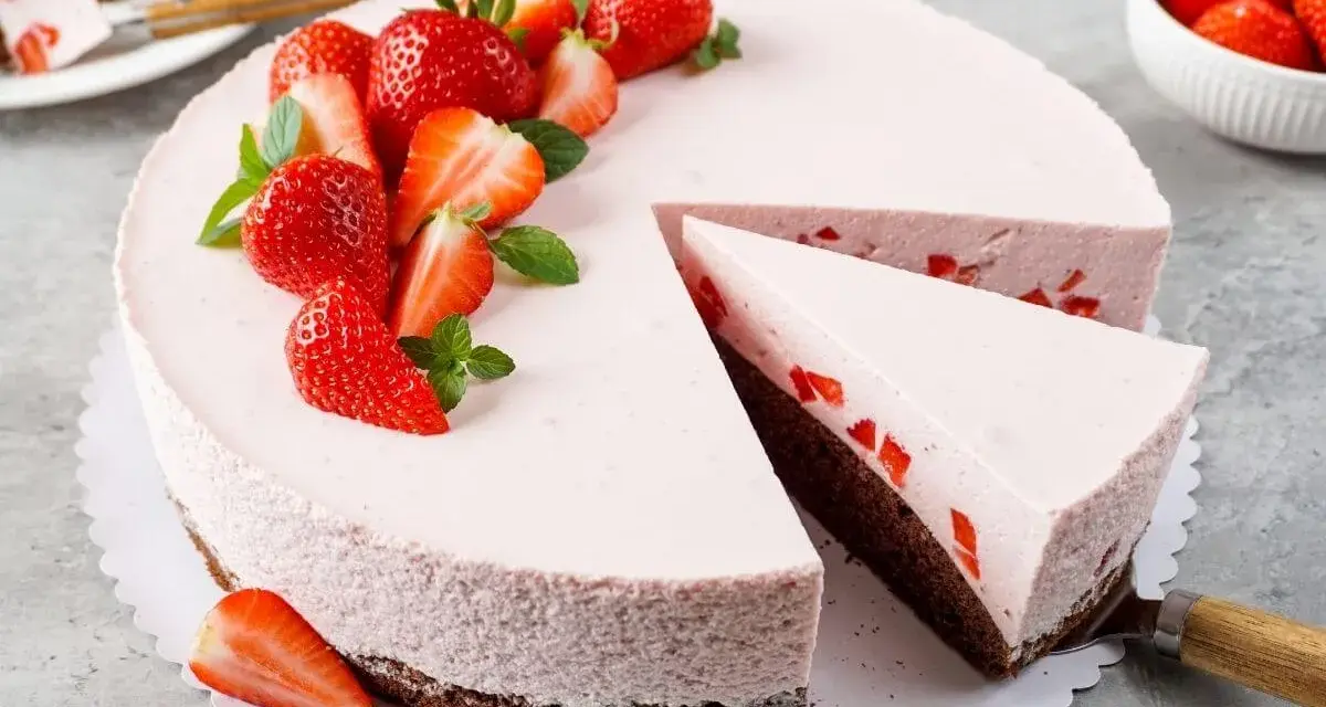 Ein köstlicher Erdbeer Schmand Kuchen in Springform, dekoriert mit frischen Erdbeeren und Minze. Ein Stück wurde bereits entnommen.