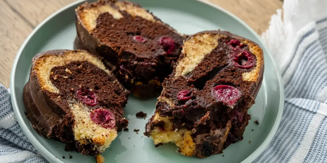 Saftiger Marmorkuchen mit Kirschen, überzogen mit Schokolade, auf einem Teller angerichtet.