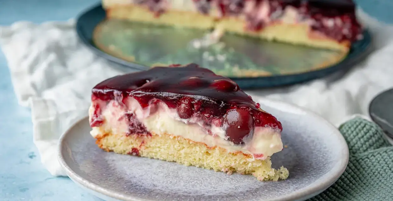 Ein saftiges Stück Kirsch-Sahne-Torte auf einem Teller, perfekt für ein schnelles obstkuchen rezept in der springform.