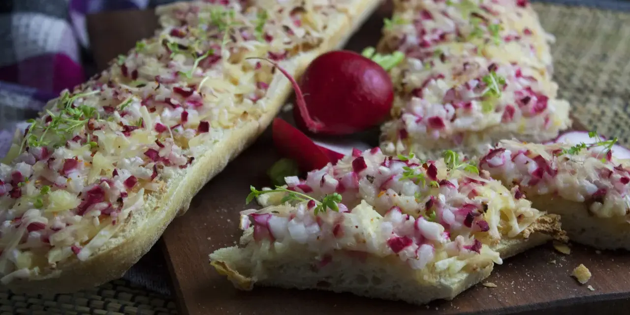 Baguette-Scheiben mit Radieschen und Käse belegt, eine köstliche Idee für Radieschen Rezepte. Frische Kresse garniert die Snacks.