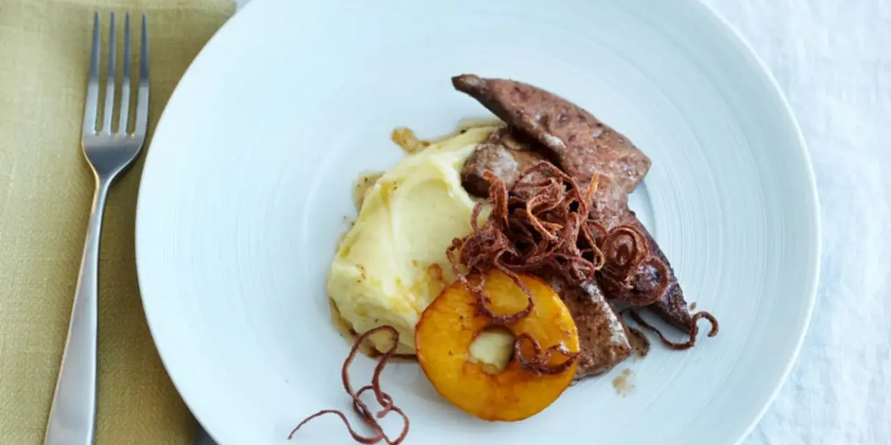 Kalbsleber rezept: Gebratene Kalbsleber mit Kartoffelpüree, Apfelring und knusprigen Zwiebeln auf einem weißen Teller.