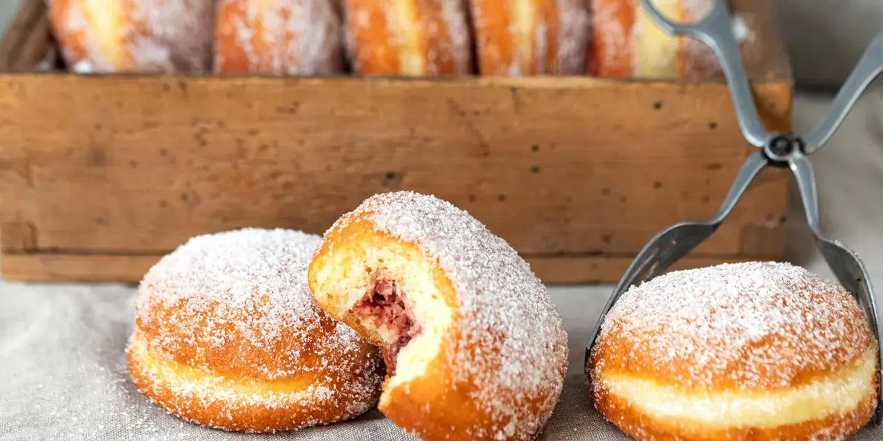 Zuckerüberzogene Berliner, eines davon mit Marmeladenfüllung, warten auf das nächste berliner rezept.