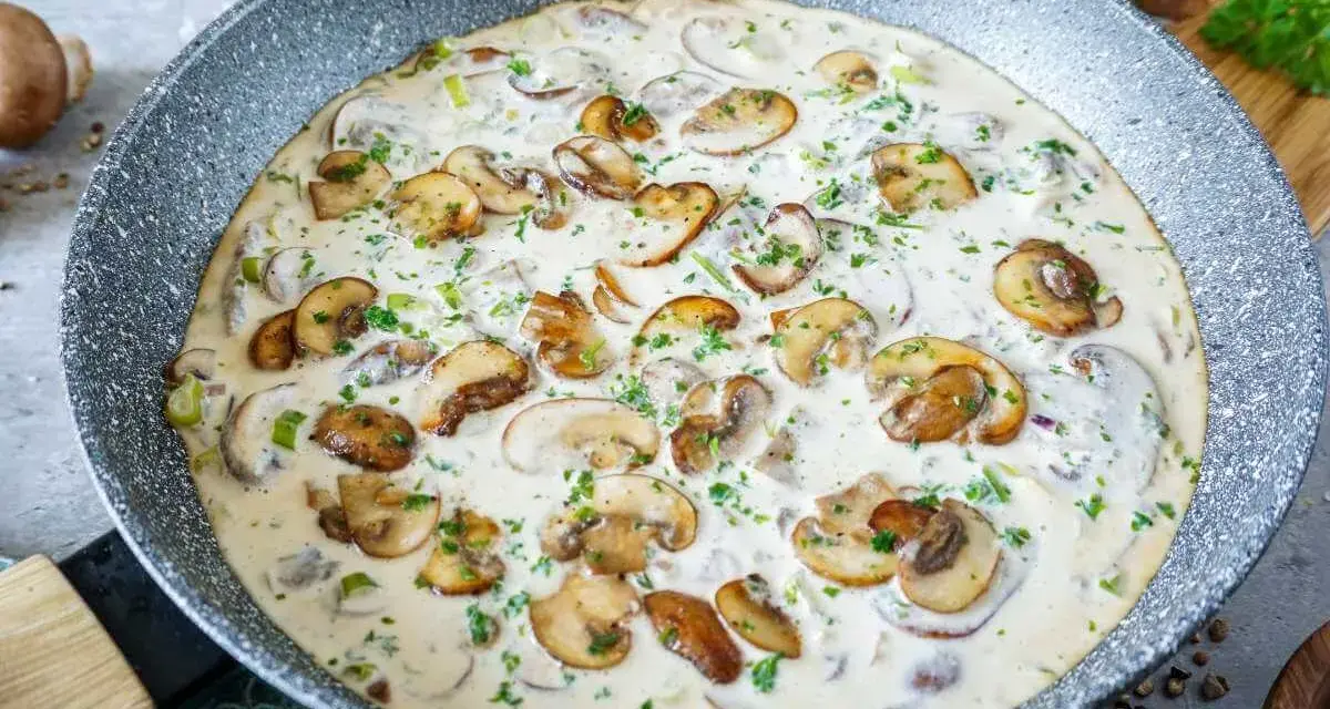 Cremige Rahmchampignons in einer Pfanne, perfekt für ein schnelles und leckeres Rahmchampignons Rezept. Mit frischer Petersilie garniert.