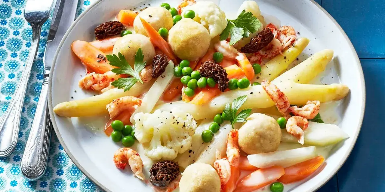 Leipziger Allerlei: Spargel, Erbsen, Karotten, Blumenkohl, Garnelen und Morcheln auf einem Teller.