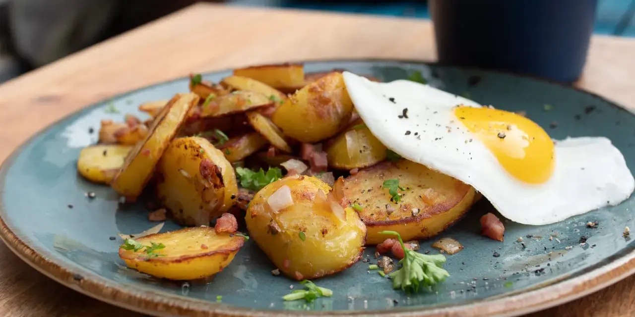 Bratkartoffeln mit Speck und einem Spiegelei, ein klassisches Rezept für ein herzhaftes Frühstück oder Abendessen.
