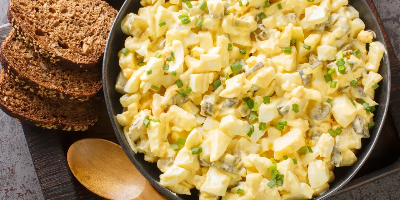 Cremiger Eiersalat mit Gurkenstückchen und Schnittlauch, perfekt für ein einfaches eiersalat rezept. Dazu passen rustikale Brotscheiben.
