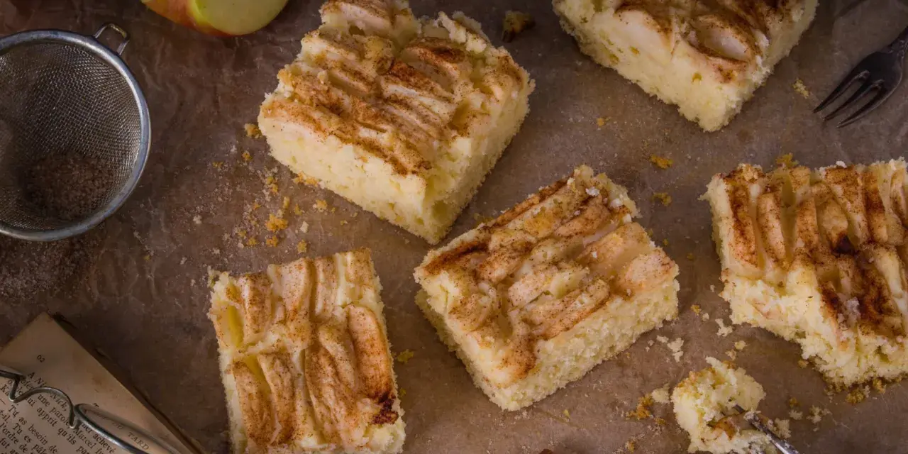 Saftige Apfel-Blechkuchen-Rezepte, bestreut mit Zimt. Ein Stück wird gerade mit einer Gabel probiert.