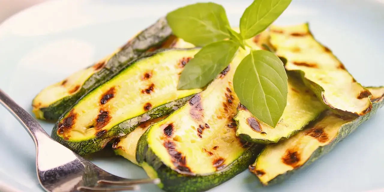 Gegrillte Zucchinischeiben mit Grillstreifen, garniert mit frischem Basilikum. Perfekt für die Sommerküche, diese Zucchini grillen marinade ist ein Genuss.