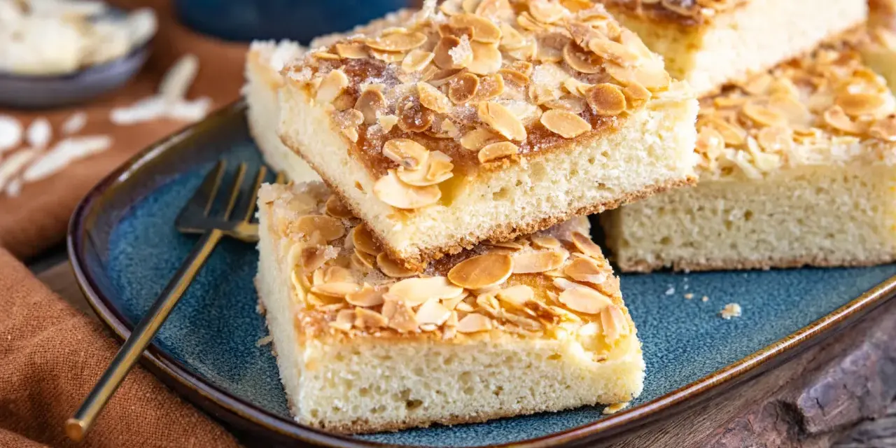 Original norddeutscher Butterkuchen mit Mandeln und Zucker bestreut, auf einem blauen Teller angerichtet.