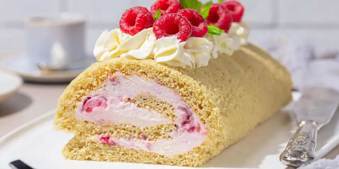 Himbeer Biskuitrolle mit Sahne und frischen Beeren, ein Genuss für jeden Kaffeetisch.