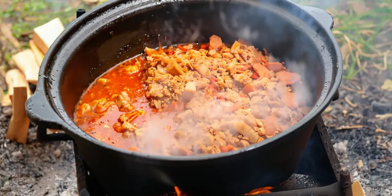 Ein dampfender Kessel mit herzhaftem Kesselgulasch, zubereitet über offenem Feuer. Das perfekte Rezept für ein rustikales Outdoor-Erlebnis.