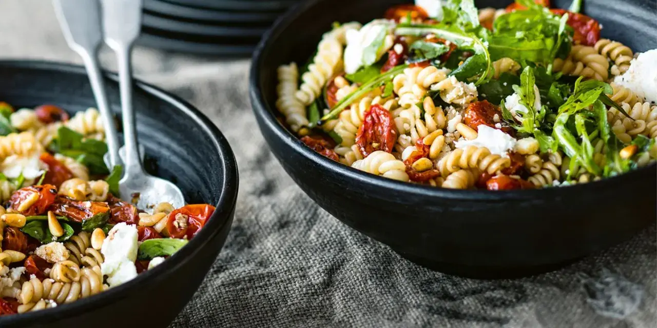 Leckerer Nudelsalat mit getrockneten Tomaten, Pinienkernen und Rucola. Ein einfaches nudelsalat rezept für den Sommer.