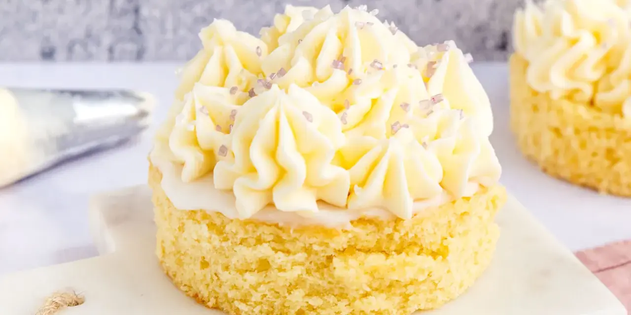 Ein kleiner Kuchen mit omas buttercreme ohne pudding, verziert mit lila Zuckerstreuseln.