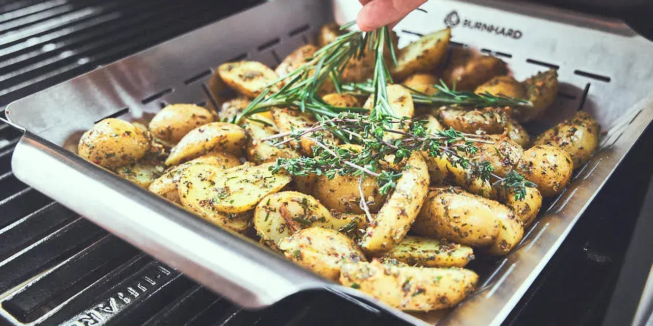 Kartoffeln mit Rosmarin und Thymian in einer Grillpfanne. Perfekt für die Drillinge Kochzeit auf dem Grill.