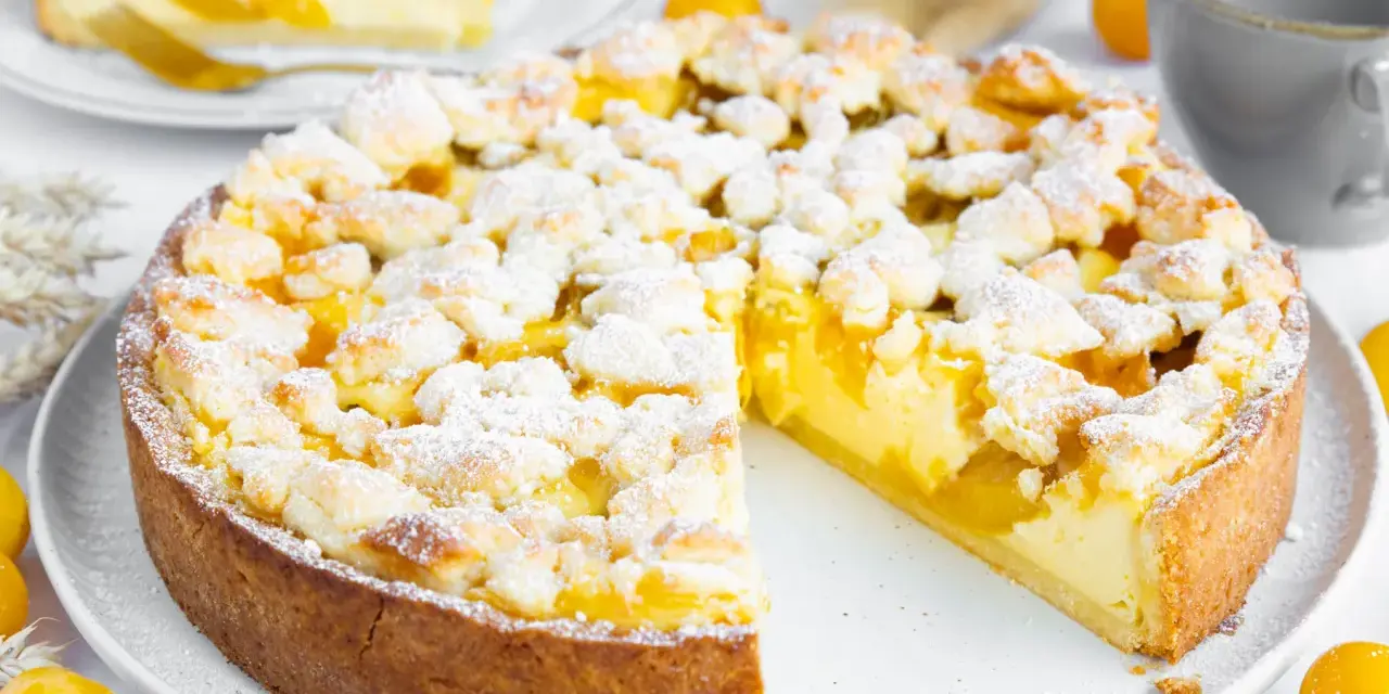 Ein saftiger Mirabellenkuchen mit Streuseln, wie ihn Landfrauen backen. Ein Stück ist bereits angeschnitten.