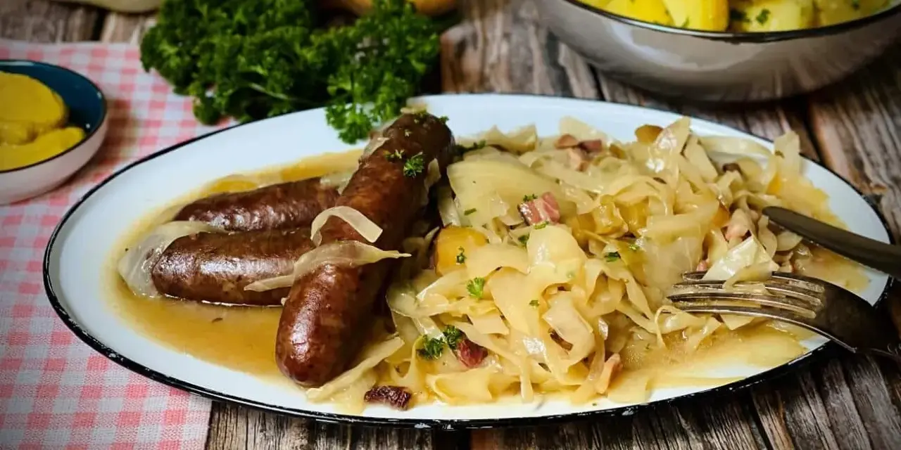 Deftige Bratwürste mit Zwiebeln auf bayrisch Kraut, garniert mit Petersilie. Dazu Salzkartoffeln und Senf.