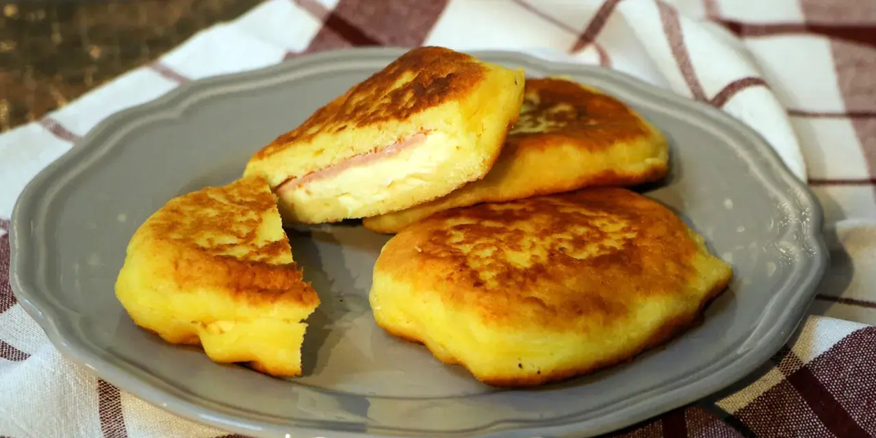 Goldbraune Kartoffel-Cordon-Bleu-Patties auf einem grauen Teller, gefüllt mit Schinken und Käse.