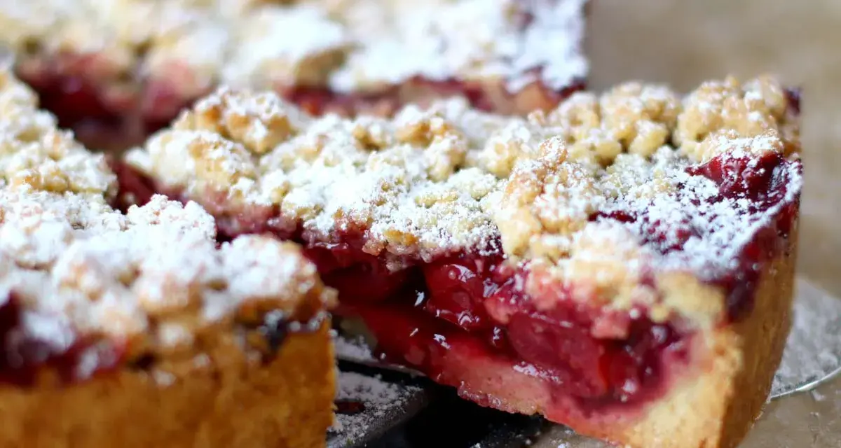 Ein saftiger Kirschstreuselkuchen, bestäubt mit Puderzucker, wartet darauf, genossen zu werden.