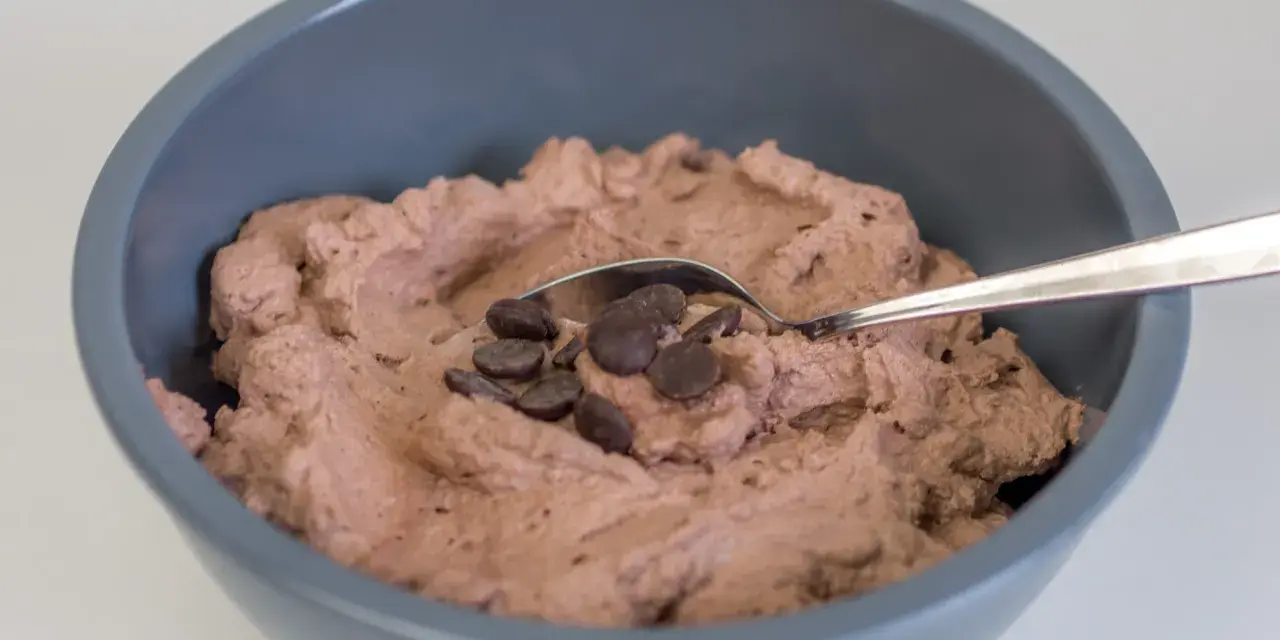 Schokosahne rezept: cremige Schokoladencreme in einer Schüssel, garniert mit Schokodrops und einem Löffel.