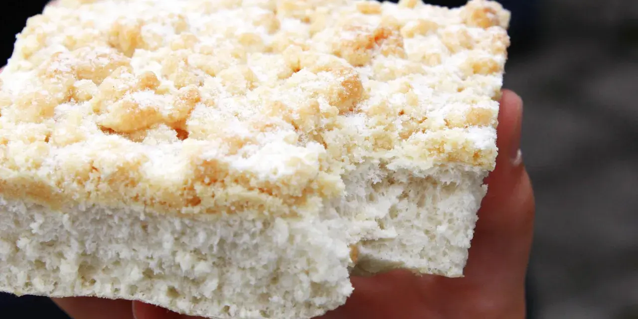 Ein Stück Kuchen mit Streuseln, die ohne Butter zubereitet wurden, liegt auf einer Hand.