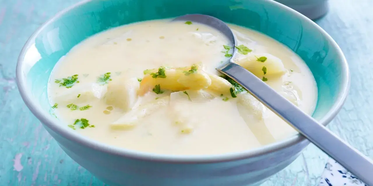 Cremige Spargelsuppe mit Petersilie in einer blauen Schüssel. Perfekt zum Spargelsuppe einfrieren für später.