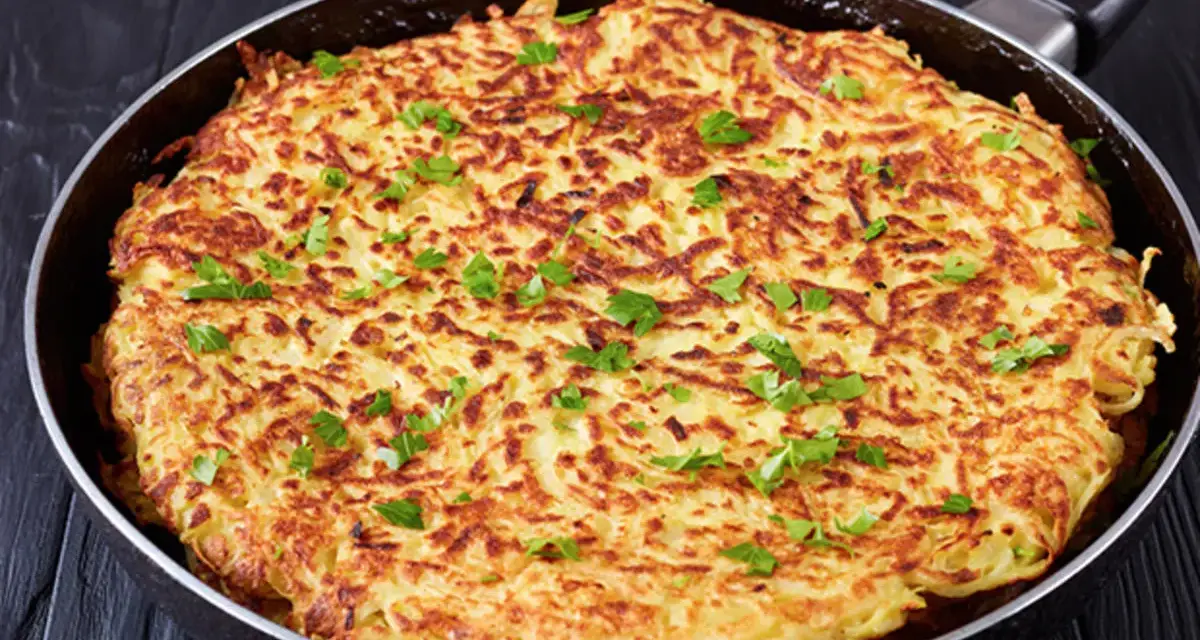Goldbraune Kartoffel-Rösti in einer Pfanne, garniert mit Petersilie. Ein einfaches und leckeres schales Rezept für jeden Tag.