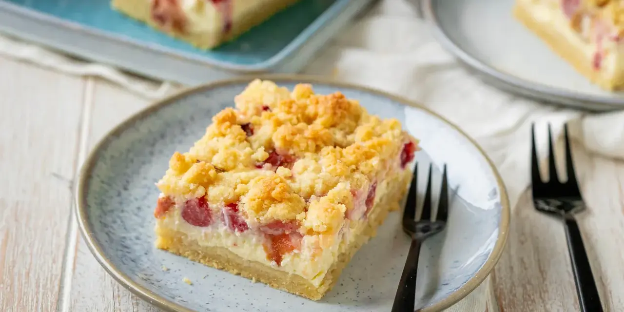 Ein Stück von Omas Rhabarberkuchen mit Quark und Streuseln auf einem Teller, bereit zum Genießen.