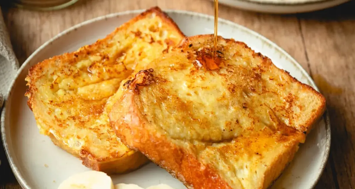 Armer Ritter, goldbraun gebraten, mit Sirup übergossen und Bananenscheiben garniert. Ein köstliches Frühstück!