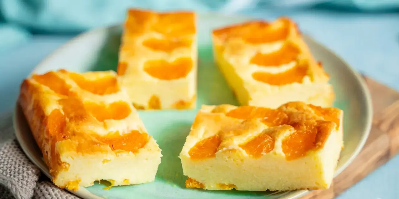Vier Stücke saftiger Mandarinen Quark Kuchen auf einem Teller, garniert mit frischen Mandarinenstücken.