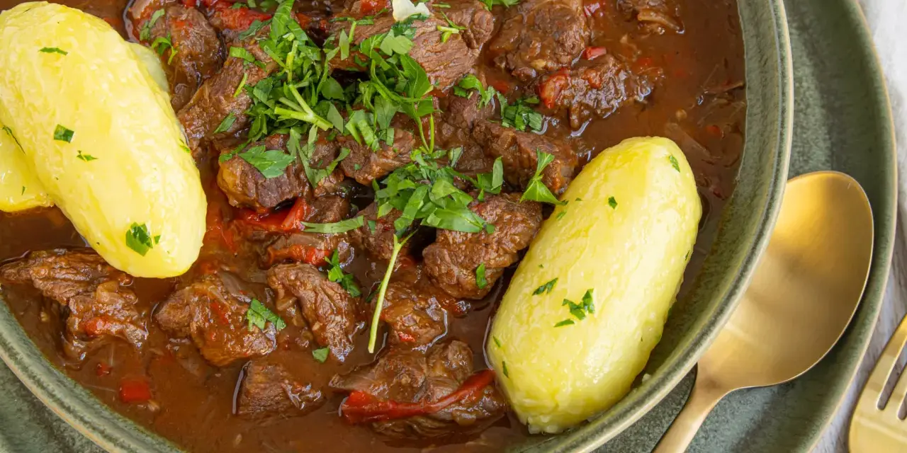 Herzhaftes Gulasch im Schnellkochtopf, serviert mit Salzkartoffeln und frischer Petersilie. Ein Klassiker, der schnell zubereitet ist.