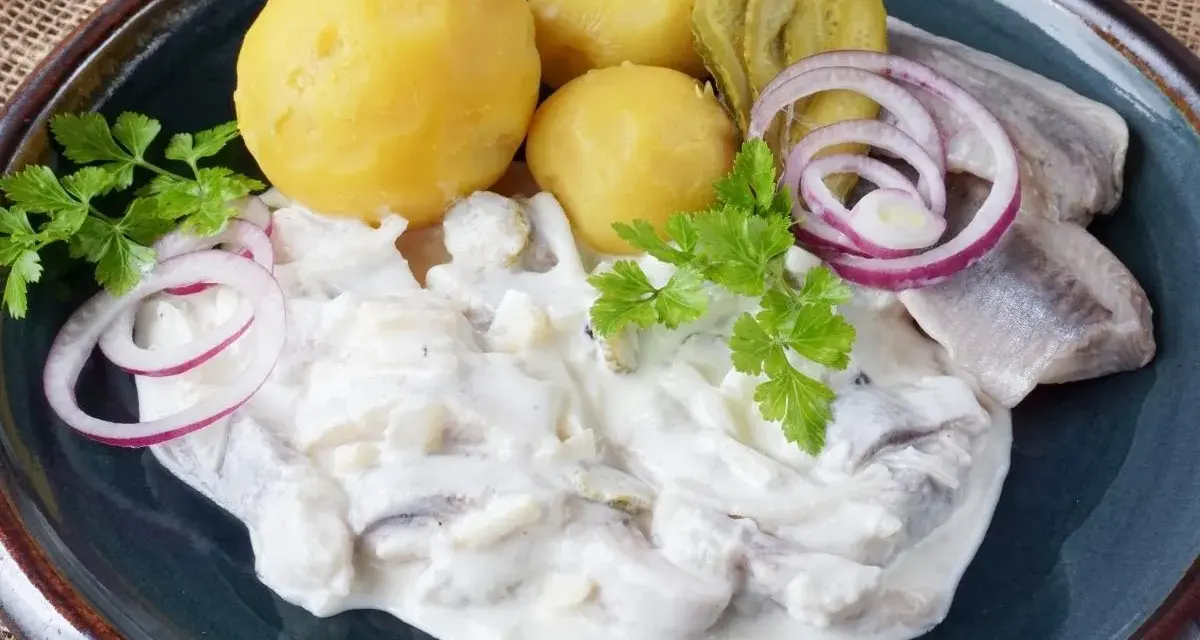Marinierter Hering in cremiger Soße mit Salzkartoffeln, Gurken und Zwiebelringen. Ein deftiges Gericht, das Appetit macht.
