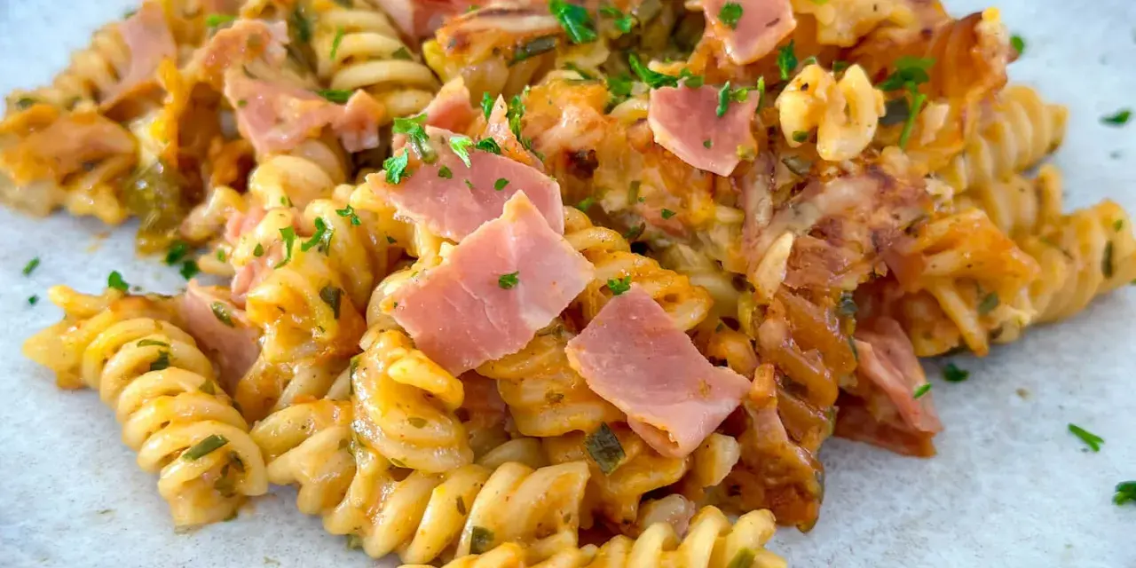 Nudel Schinken Gratin mit Käse überbacken, garniert mit Petersilie. Ein herzhaftes Gericht, das zum Genießen einlädt.