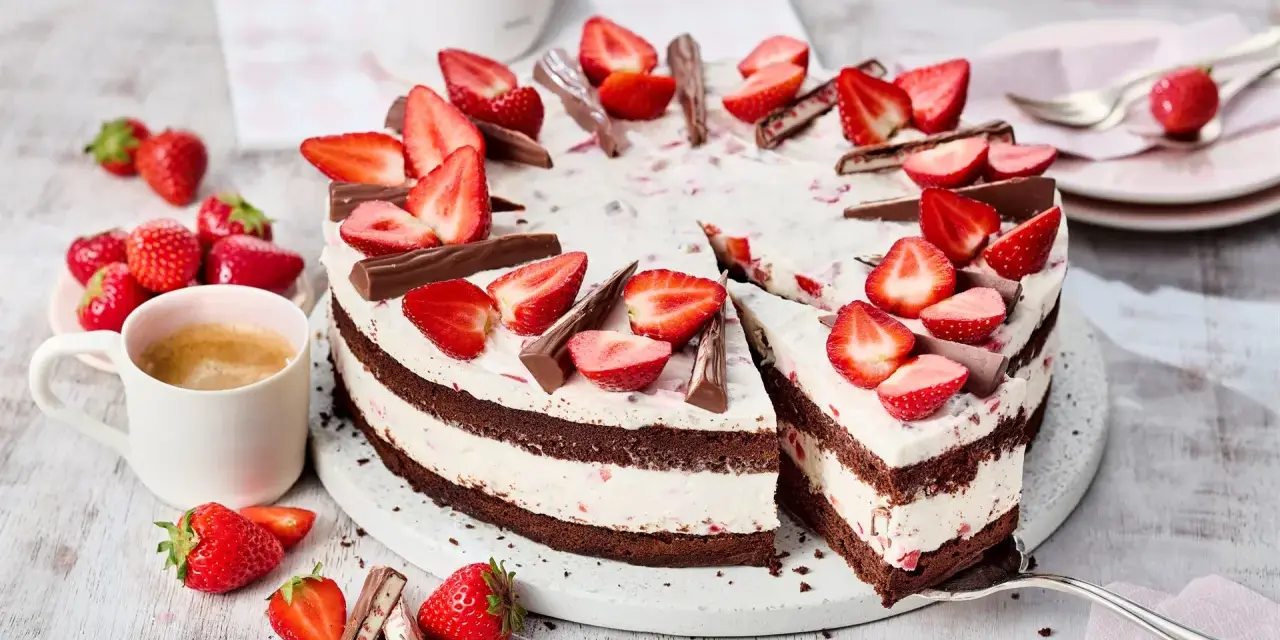 Eine köstliche Yogurette Torte mit frischen Erdbeeren und Schokostückchen, serviert mit einer Tasse Kaffee.