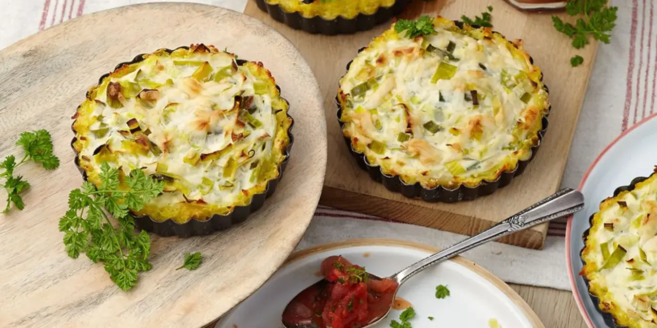 Kleine herzhafte Lauch-Tartelettes mit cremigem Belag, garniert mit Petersilie. Perfekt für Lauch Rezepte.
