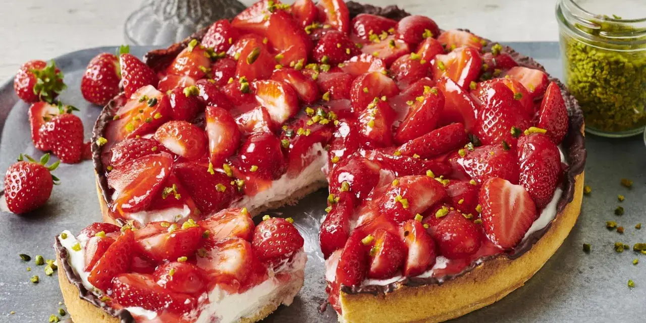 Saftiger Erdbeerkuchen mit frischen Erdbeeren, Sahne und gehackten Pistazien. Ein Traum für alle, die Rezepte mit Erdbeeren lieben!