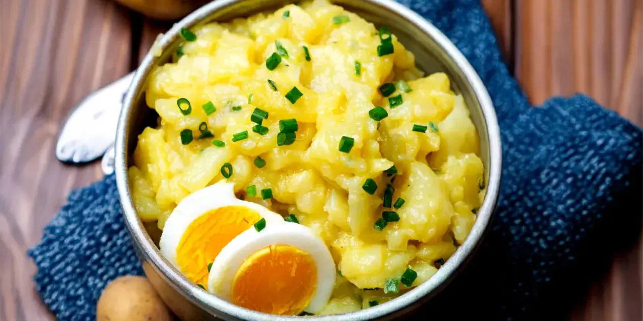 Omas Kartoffelsalat, cremig und mit Schnittlauch bestreut, serviert mit gekochten Eiern. Ein Klassiker, der immer schmeckt.