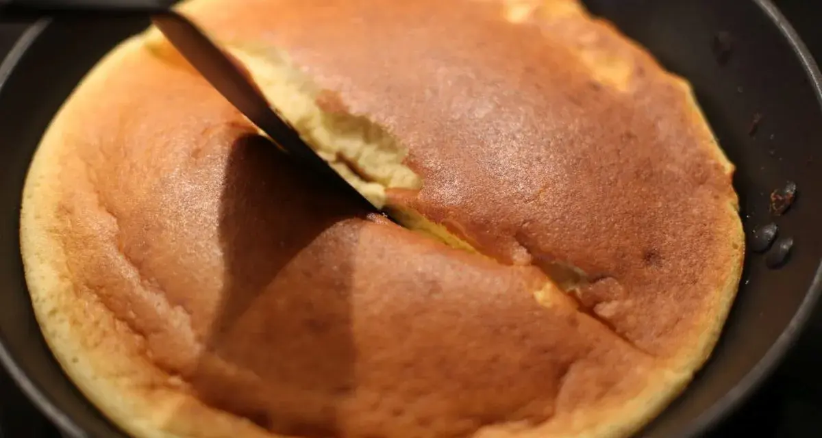 Ein goldbrauner Kaiserschmarrn wird in der Pfanne mit einem Messer zerteilt. Das perfekte Rezept für diesen Klassiker!