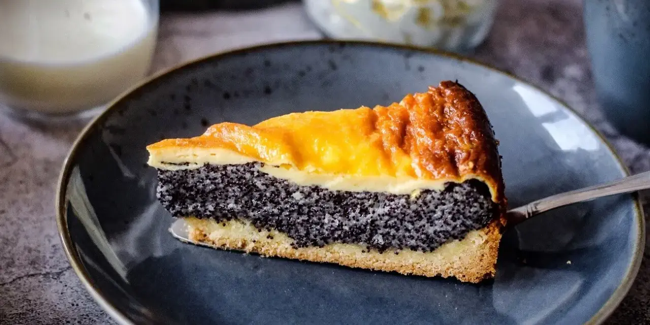 Ein saftiges Stück Mohnkuchen mit Pudding-Schicht auf einem blauen Teller, bereit zum Genuss.