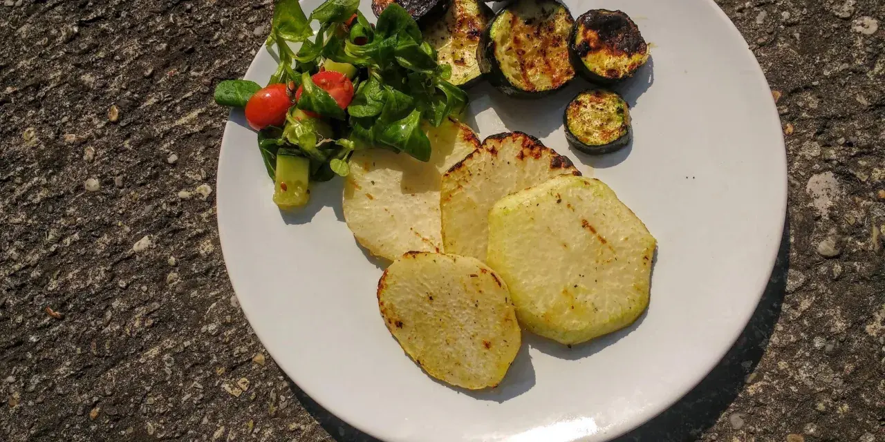 Gegrillte Kohlrabi-Scheiben mit Zucchini und einem kleinen Salat. Ein leckeres Gericht, das Lust auf Kohlrabi grillen macht.