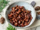 Schüssel mit glasierten, gebrannten Mandeln, zubereitet im Airfryer. Dekoriert mit Tannenzapfen und Tannenzweigen.