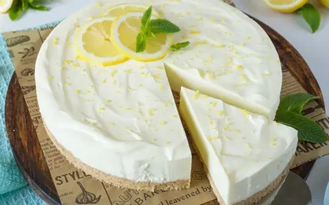 Cremige Philadelphia Torte mit Zitronenscheiben und Minze, ein Stück wurde bereits entnommen.