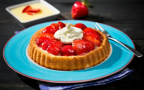 Erdbeerkuchen mit fertigboden, belegt mit frischen Erdbeeren und Sahne, auf einem blauen Teller.