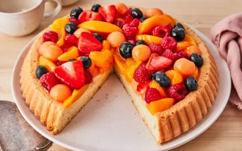 Ein leckerer Obstboden belegt mit Erdbeeren, Himbeeren, Blaubeeren, Aprikosen und Melonenbällchen.