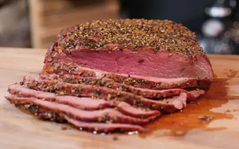 Perfekt gegarter Roastbeef Braten, saftig und rosa, mit einer würzigen Kruste aus Pfeffer und Kräutern, auf einem Holzbrett.