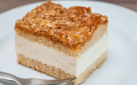 Ein Stück Bienenstich-Kuchen mit cremiger Füllung und karamellisierten Mandeln. Perfekt für das Bienenstich Rezept!