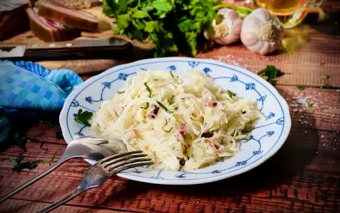 Ein Teller mit Krautsalat, garniert mit Petersilie. Daneben liegen Gabel und Löffel. Ein leckeres Krautsalat Rezept für dich!