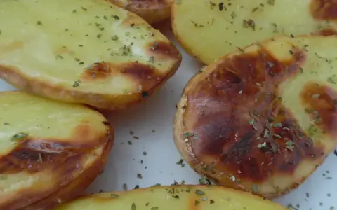 Heißluftfrittierte Kartoffelspalten, wie kleine, goldbraune Ballons, bestreut mit Kräutern.